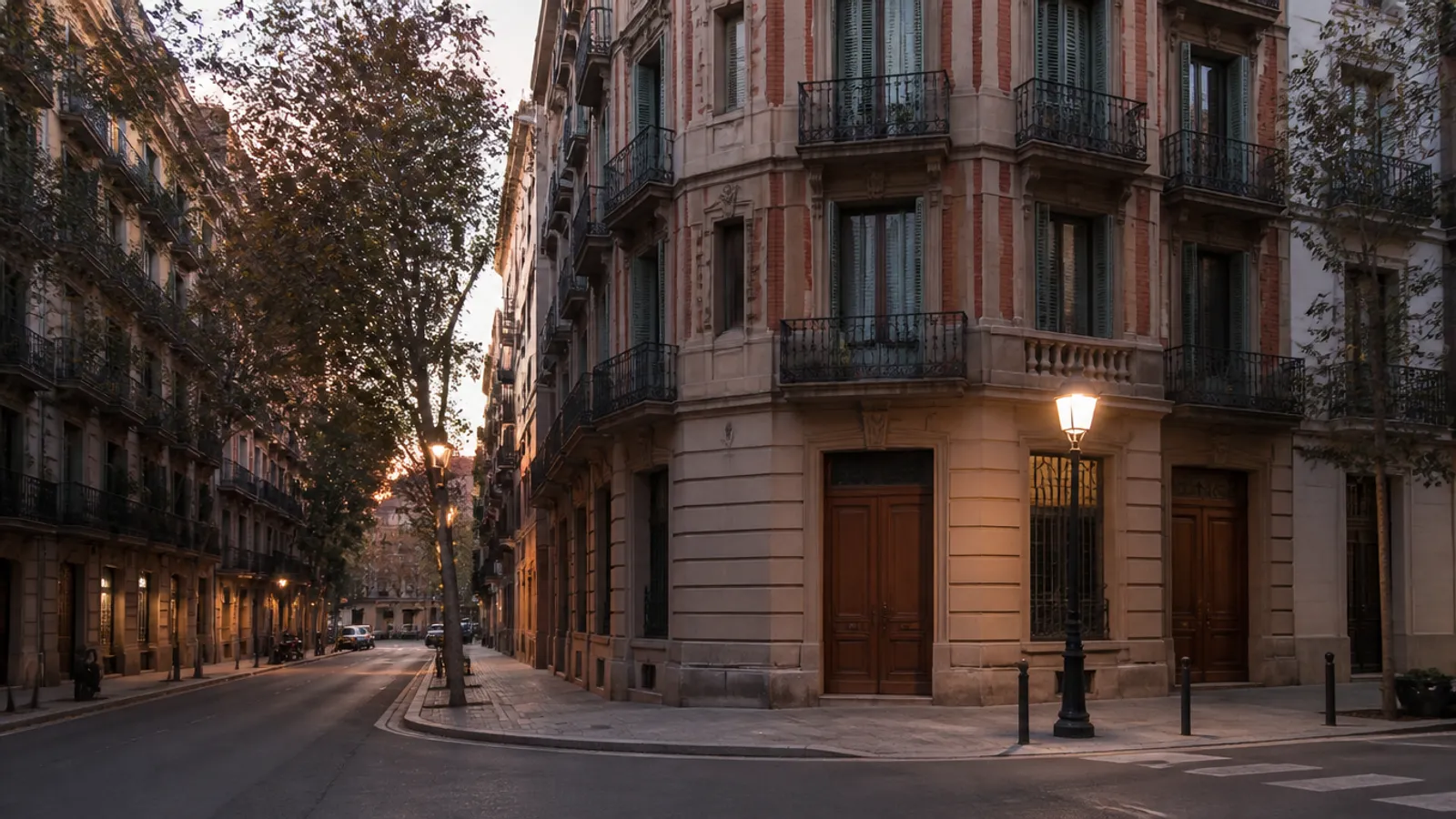 Chaflán del Eixample de Barcelona al atardecer, con fachadas de piedra, balcones de forja y portales residenciales